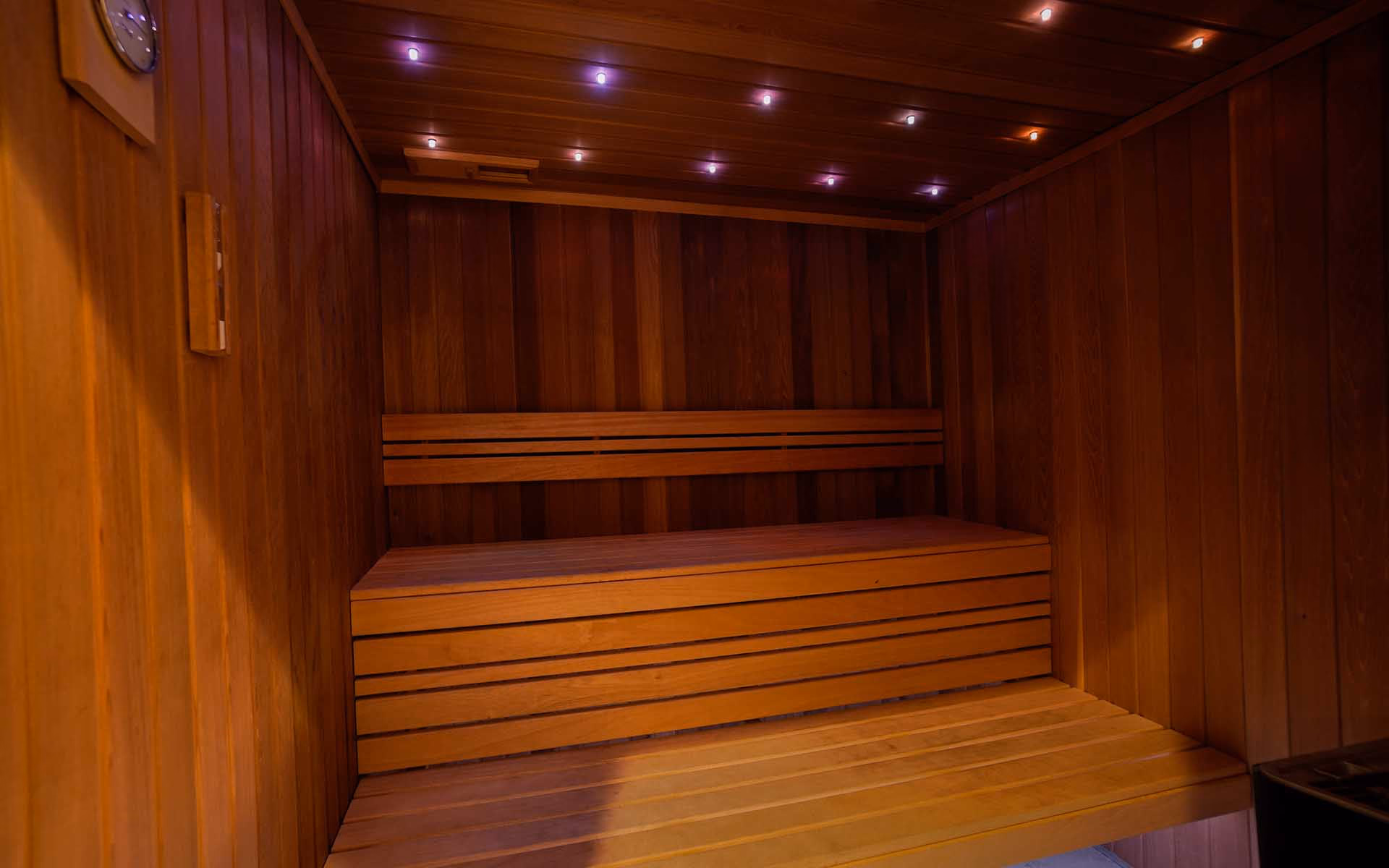 Sauna fińska z drewnianymi ławami i kolorowym oświetleniem