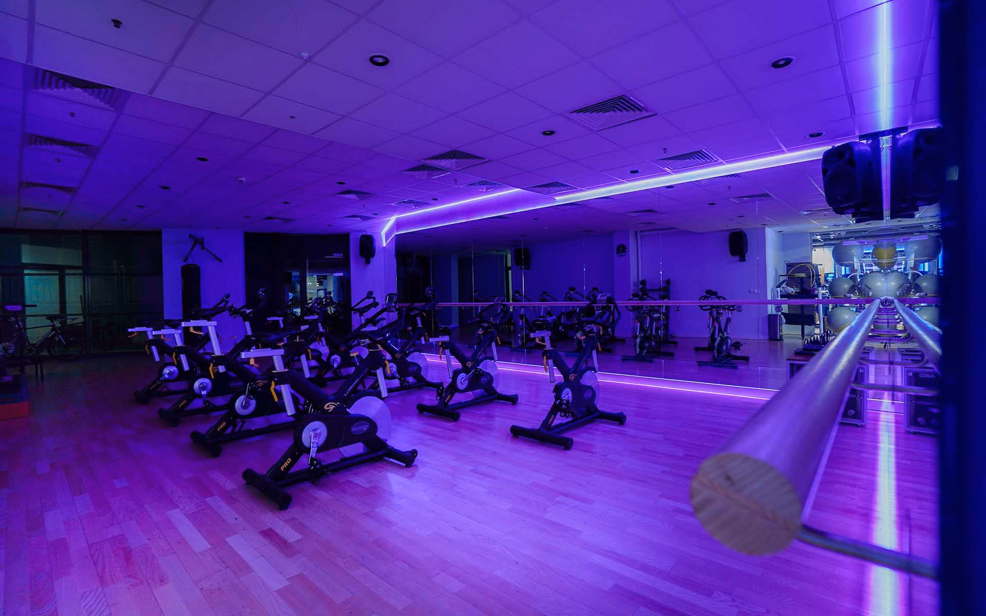 Studio fitness z rowerami spinningowymi w fioletowym oświetleniu